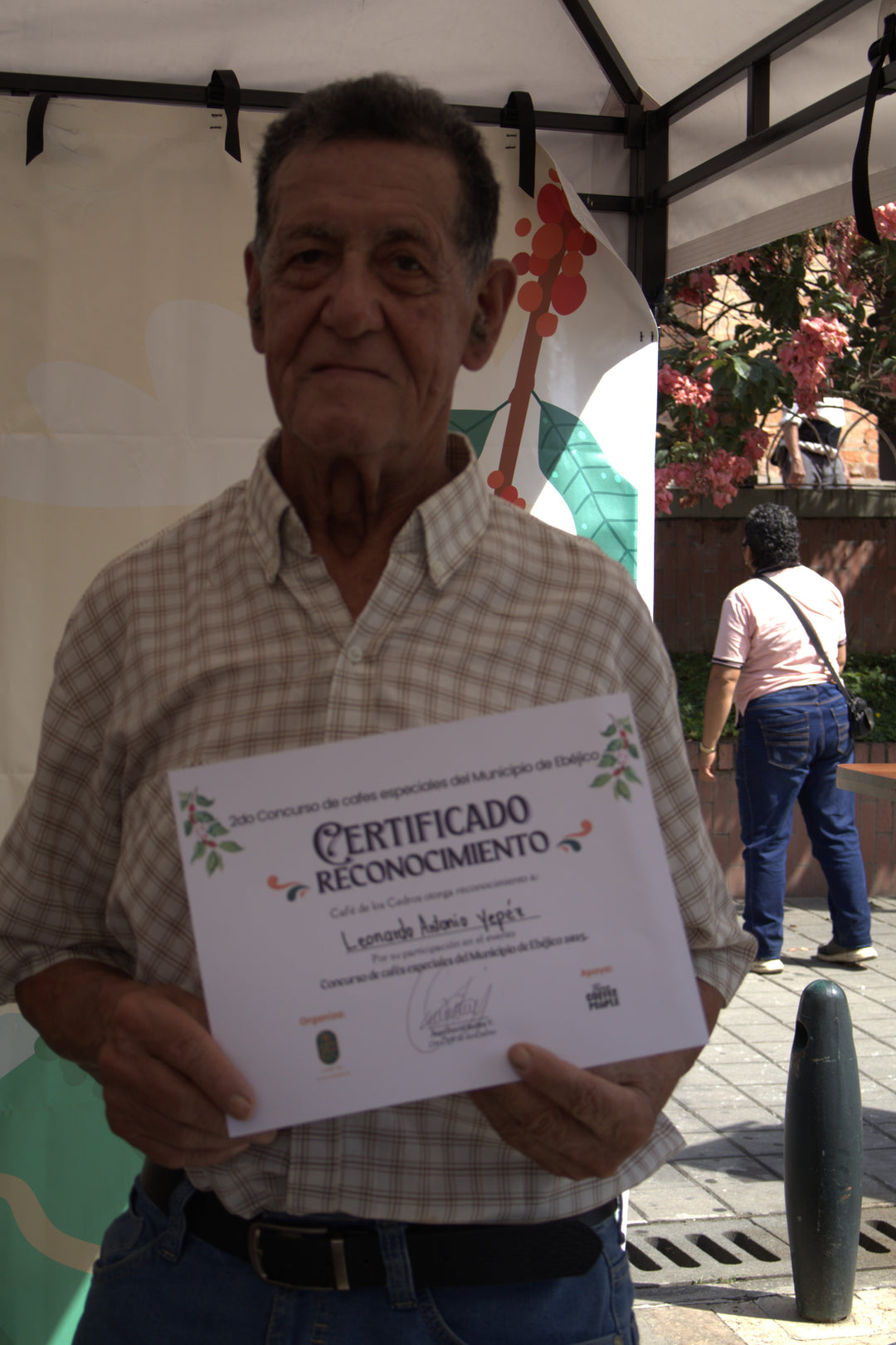 Person holding a certificate outdoors with a blurred background